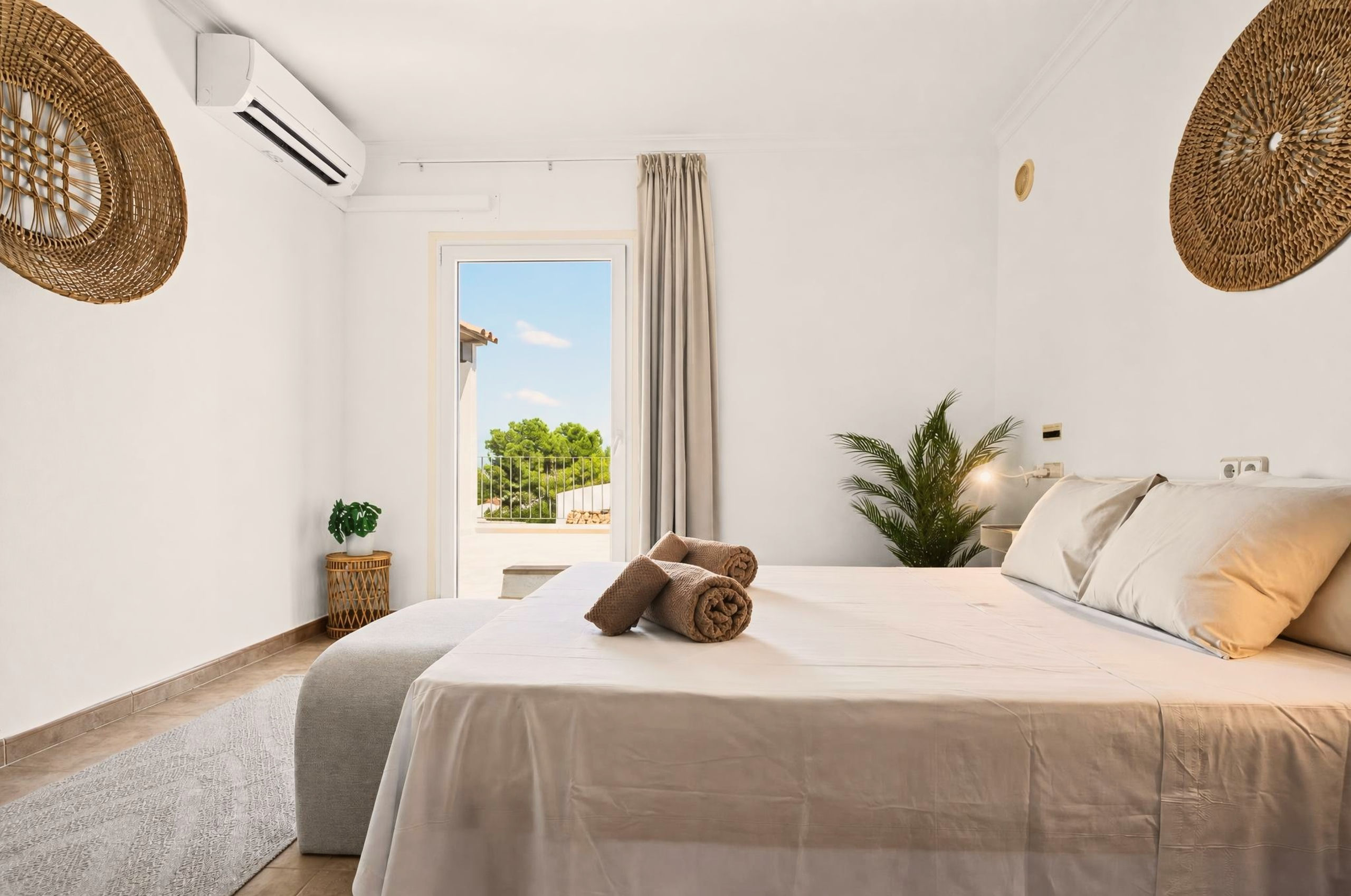 Dasselbe Schlafzimmer vom Fußende aus: über der Balkontür sitzt die Klimaanlage, draußen rahmen Pinien den Blick.